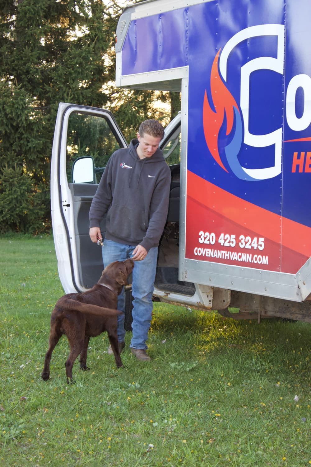 Young man with brown dog by a vehicle featuring Covenant Health Services branding.